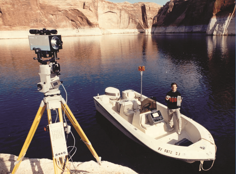 Dredging professional stands in a boat with their LTI Hydro system on shore, in 1986.